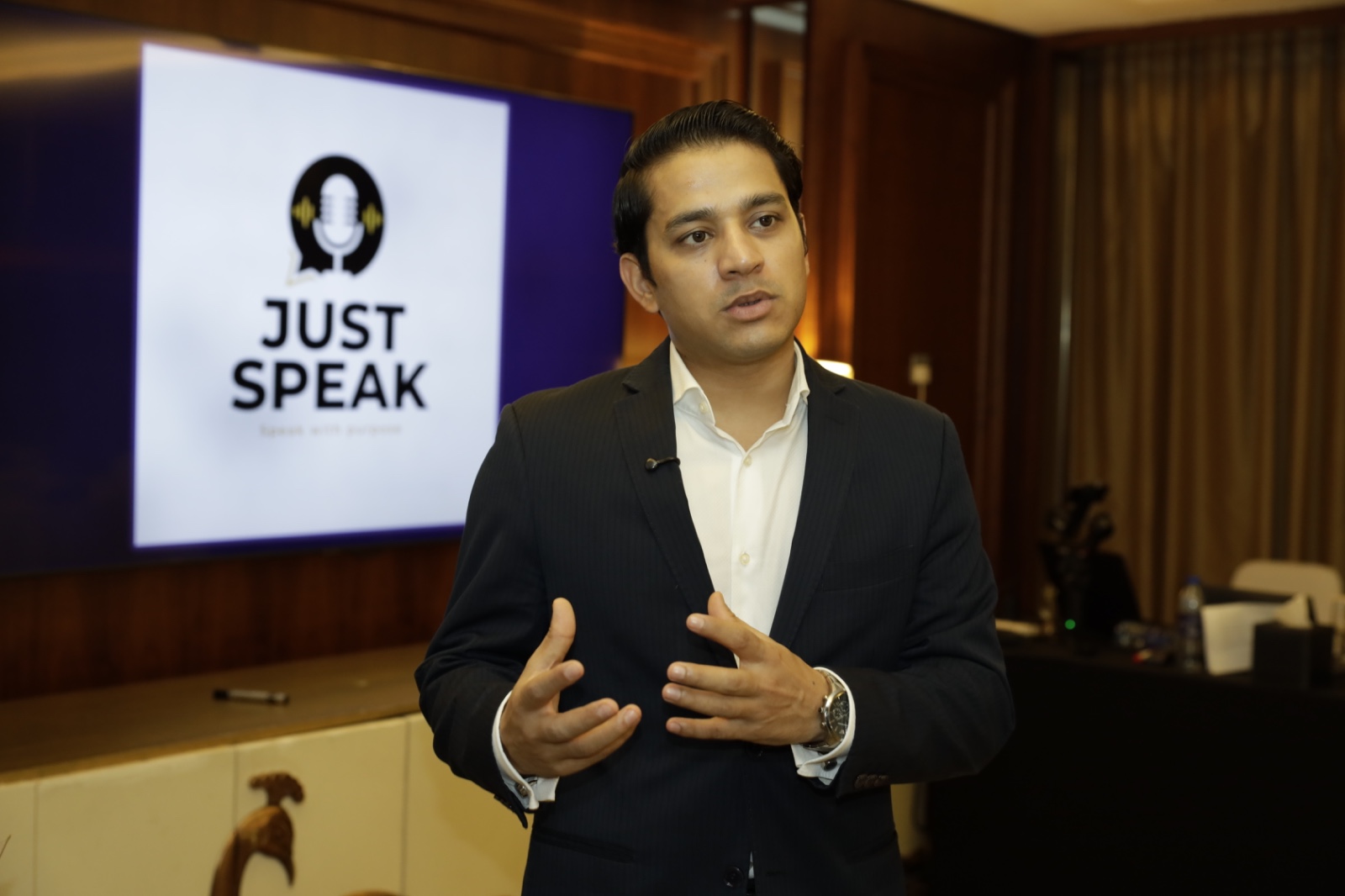 Speaker presenting beside the JUST Speak logo screen